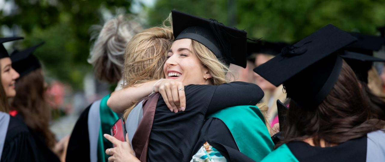 Two women hug during graduation.